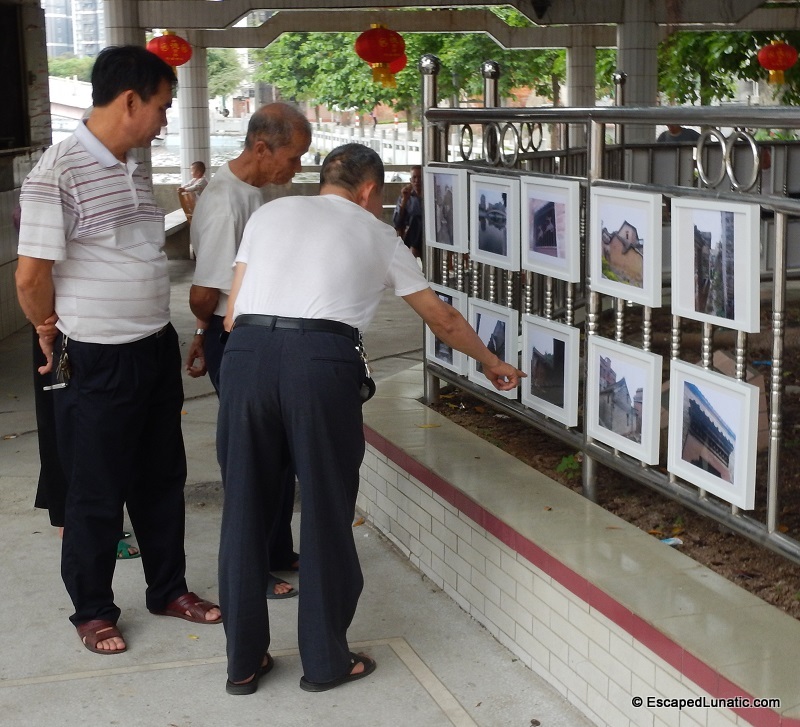Locals viewing art exhibit about historic buildings in the village.